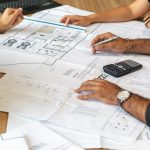 people reviewing architectural blueprints on desk